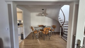 A dining area with a glass table, six chairs, and a ceiling fan.
