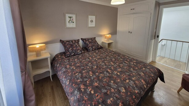 A bedroom with a bed, bedside lamps, a wardrobe, and a ceiling light.