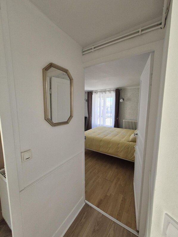 A bedroom with a bed, a radiator, and a window with curtains.