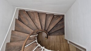 A spiral staircase with wooden steps and a white wall.