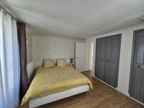 A bedroom with a bed, two pillows, a nightstand, a wardrobe, and a door.