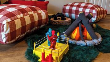 A room with a checkered bedspread, a small wooden bed, a toy boxing ring, and a plush toy.