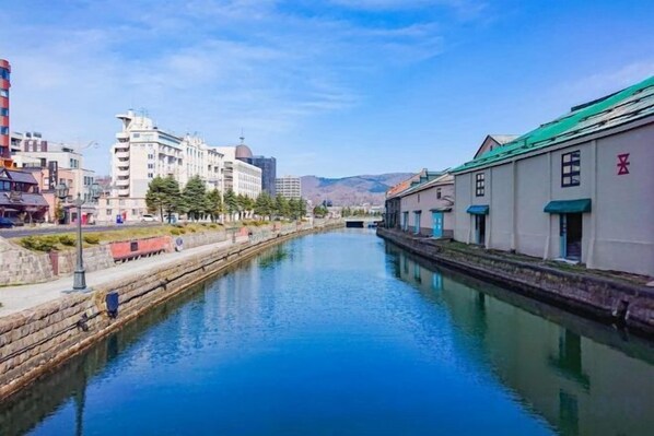 Un canal flanqueado por edificios, cielo despejado y montañas a lo lejos.