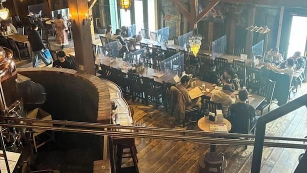 A spacious restaurant with high ceilings and exposed beams, featuring multiple dining areas with patrons and staff. - Minami Otaru House Sakaimachi (Otaru)