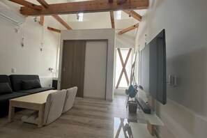 Een moderne woonkamer met een bank, een salontafel en een aan de muur bevestigde televisie.