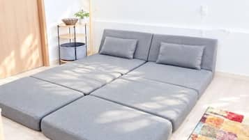 A modern, grey sectional sofa with a matching headboard in a bright room with a wooden floor.