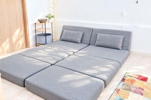 Un sofá seccional moderno gris con cabecera a juego en una habitación luminosa con piso de madera.