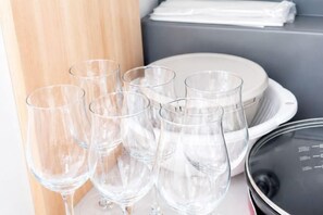 Juego de vasos de vidrio transparentes y platos blancos sobre una mesa, con una taza medidora y un recipiente negro cerca.