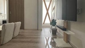 A modern interior with a wooden floor, a sliding door, a flat-screen TV, and a plant. - Minami Otaru House Sakaimachi (Otaru)