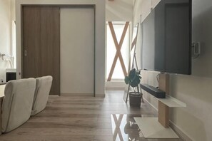 Un intérieur moderne avec un plancher en bois, une porte coulissante, un téléviseur à écran plat et une plante.