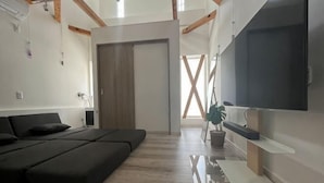 A modern living room with a sofa, a TV, and a potted plant. - Minami Otaru House Sakaimachi (Otaru)