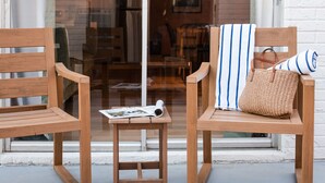 Deux chaises en bois, une petite table placée entre elles, un magazine sur la table et un sac en tissu posé sur l’une des chaises.