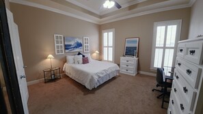 A bedroom with a bed, bedside lamps, a dresser, and artwork on the walls. - Courtyard Haven Stylish 3BR Retreat (Prairieville)