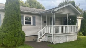Ein eingeschossiges Haus mit überdachter Veranda und einer kleinen Treppe zum Eingang.