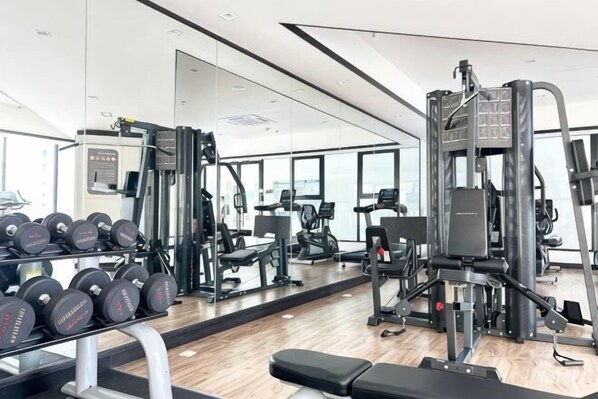 A gym with weightlifting equipment, a bench, and a mirror reflecting the space. - Paradigm Residences 1 BR, above Paradigm Mall ,up to 5 Person (Johor Bahru)