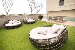 A rooftop lounge with circular wicker sofas and a small pool area. - Paradigm Residences 1 BR, above Paradigm Mall ,up to 5 Person (Johor Bahru)
