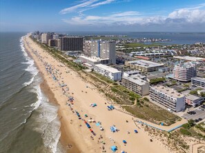 A coastal cityscape with a beach, high-rise buildings, and a marina. - Sandy Square – Direct Oceanfront Condo 3BR • 2BA • Sleeps 11 (Ocean City)