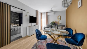 A modern living room with a dining area, a TV, and a sofa. - Praga Apt - Parking, Terrace - by Rentujemy (Warszawa)