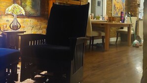 Een woonkamer met een bakstenen muur, een zwarte stoel, een tafel met stoelen en een raam.