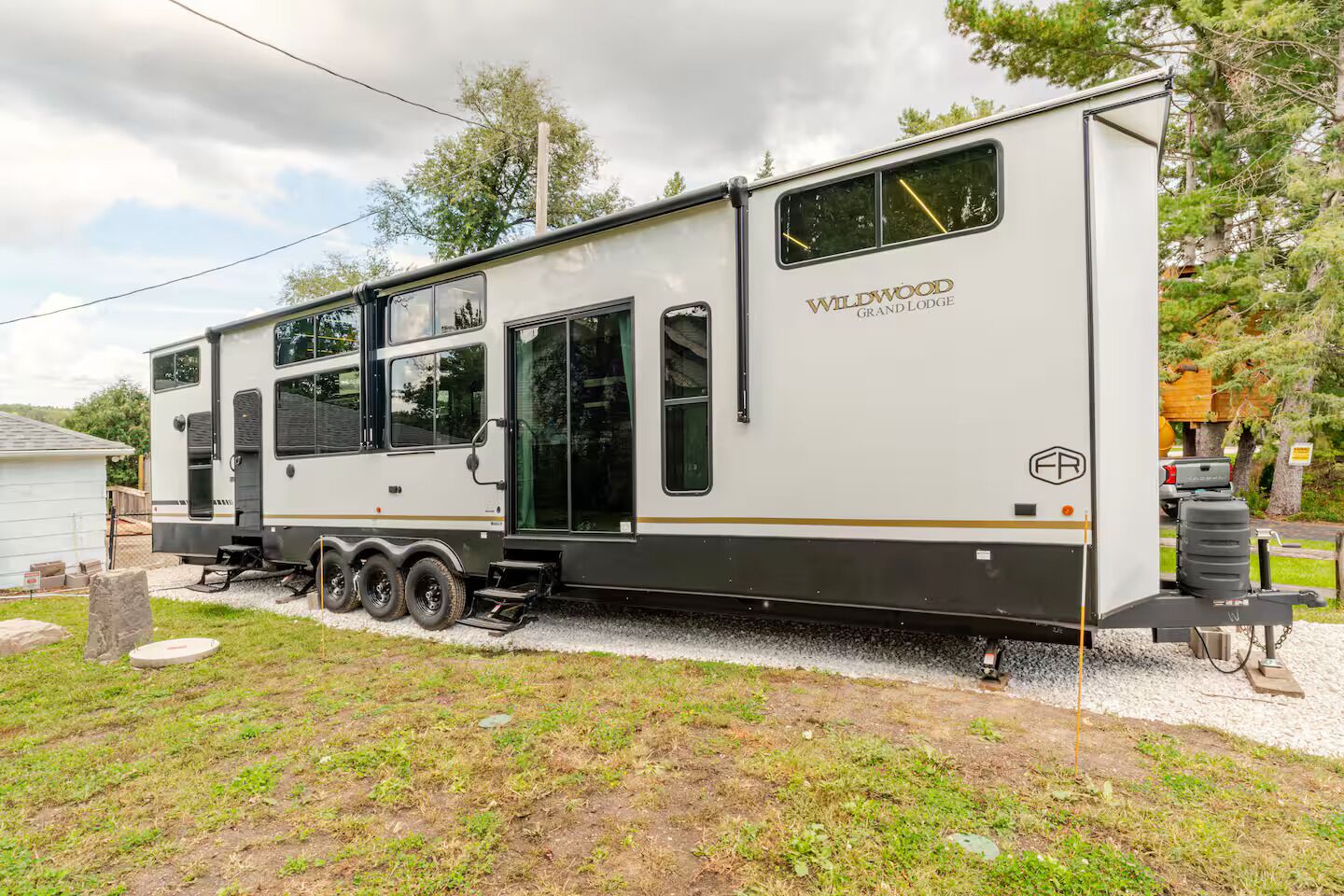 A recreational vehicle with the name "Wildwood Grand Lodge" on its side, equipped with multiple windows and a flatbed trailer.