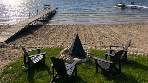 Une plage au bord d’un lac, avec une jetée, des chaises et une zone herbeuse.