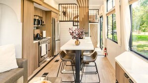 Une cuisine moderne avec un coin repas, des meubles en bois et une vue sur l’extérieur.