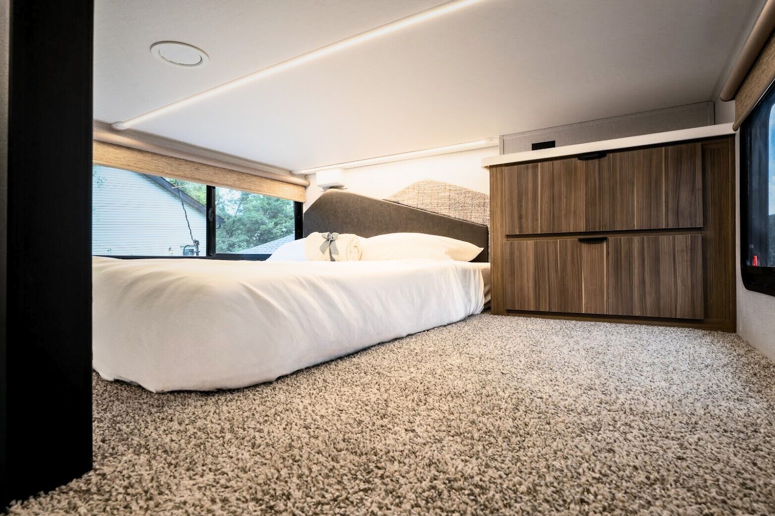 Un dormitorio con una cama, un armario de madera y suelo alfombrado.