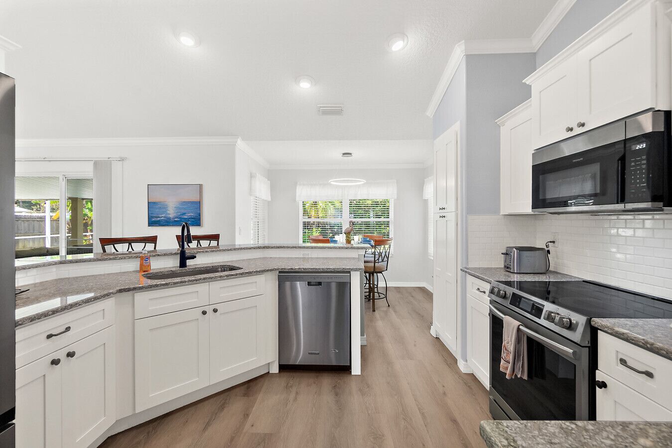 A modern kitchen with white cabinetry, a dishwasher, a stove, and a microwave.