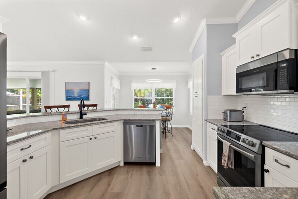 A modern kitchen with white cabinetry, a dishwasher, a stove, and a microwave.