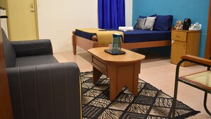 Una habitación con una cama, un sofá, una mesita con hervidor y una silla.