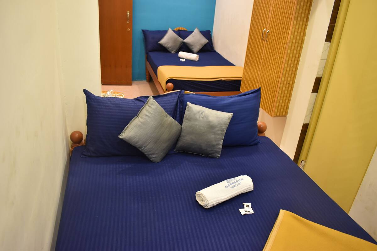 A hotel room with two beds, each with blue bedding and pillows, a wooden headboard, and a yellow accent wall.