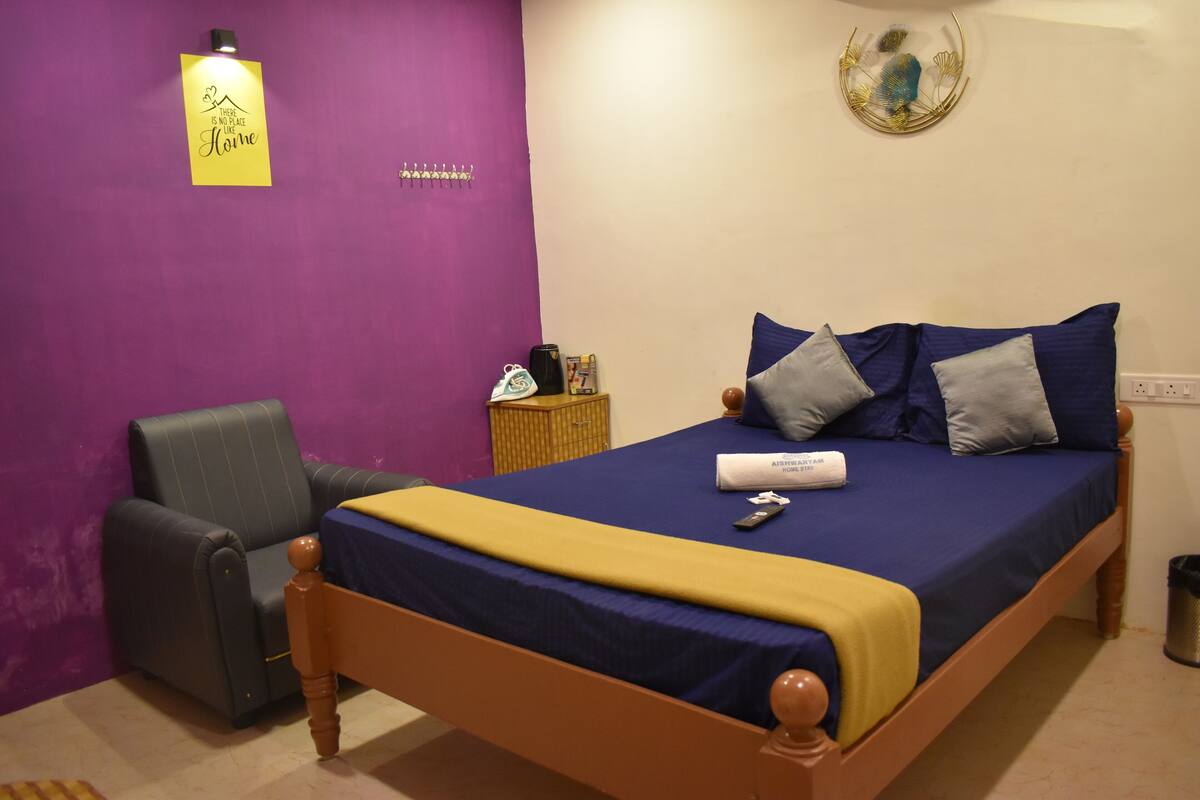 A bedroom with a bed, a chair, a nightstand, and a wall with a sign.