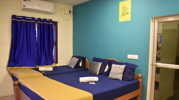 Una cama doble con ropa de cama azul y amarilla, un cabecero de madera y una ventana con cortinas azules.