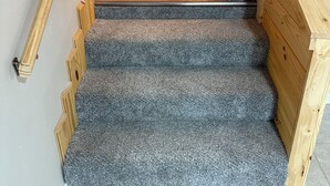 Een houten trap met beklede treden en een leuning.