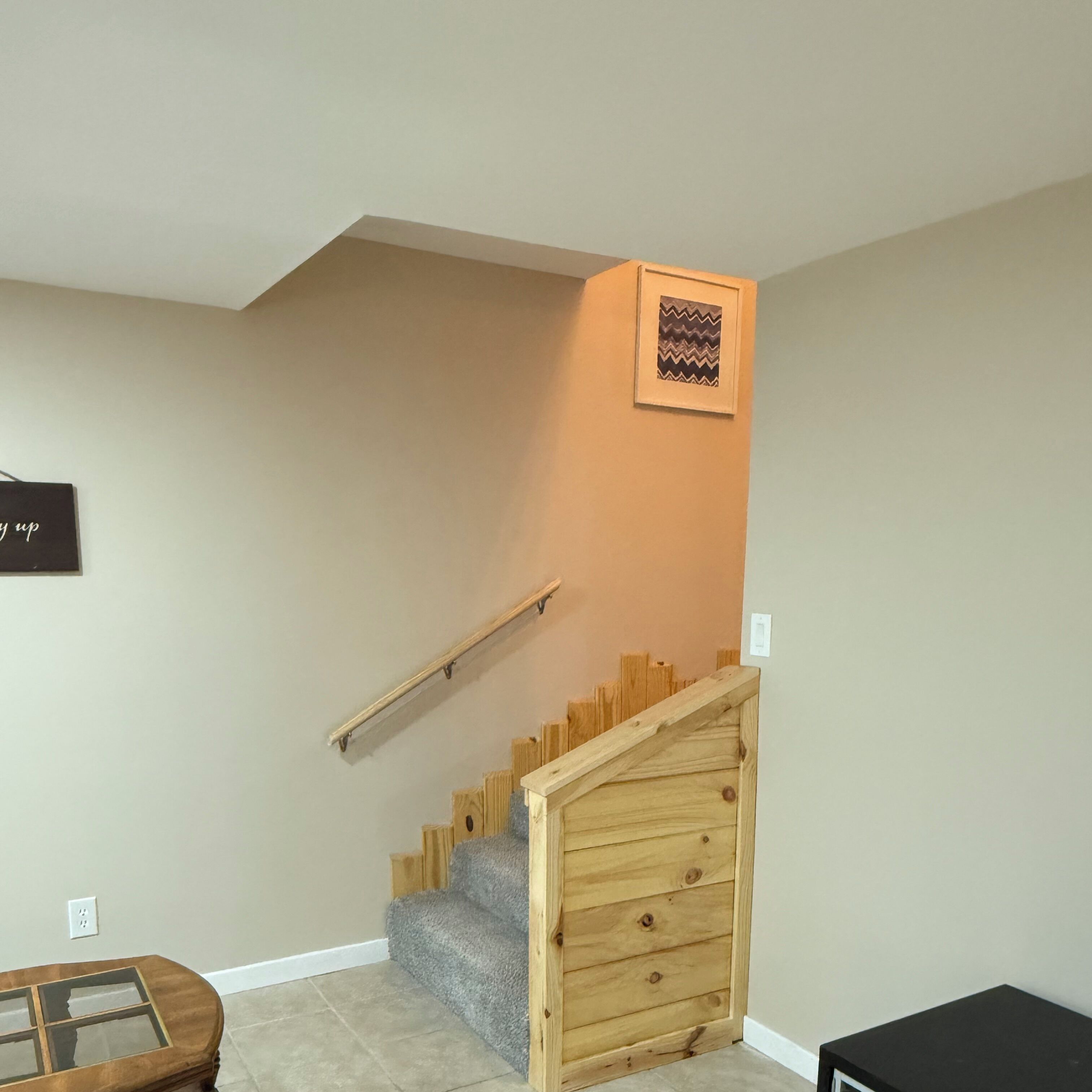 A staircase with a wooden handrail and a carpeted landing.