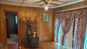 Una habitación acogedora con chimenea, muebles de madera y vistas a través de cortinas.