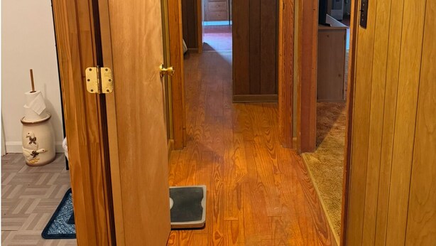 Un pasillo de madera con una puerta corredera que da a una zona de cocina.