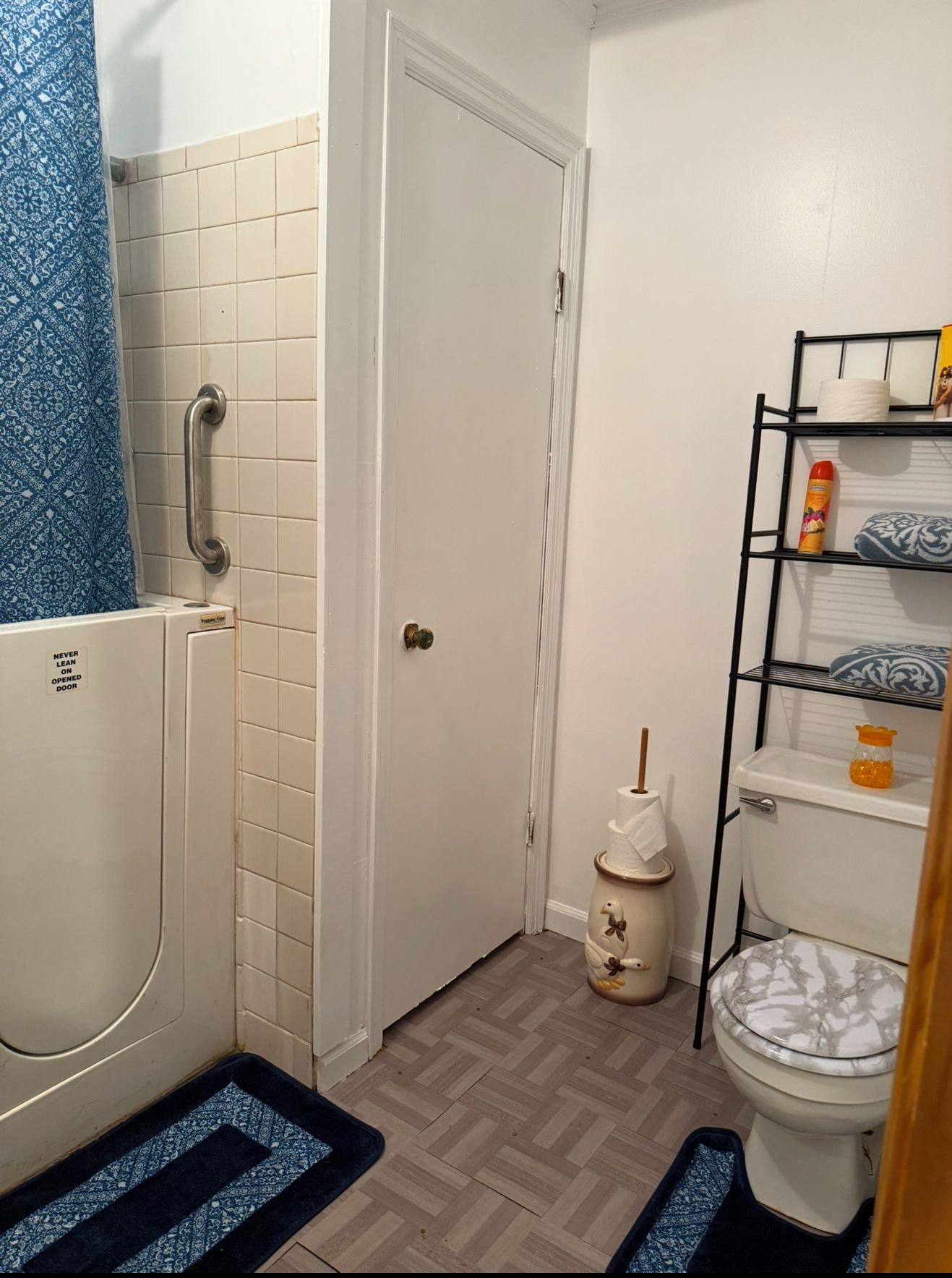 Une petite salle de bain avec une douche, des toilettes et une étagère où sont rangés les articles de toilette.