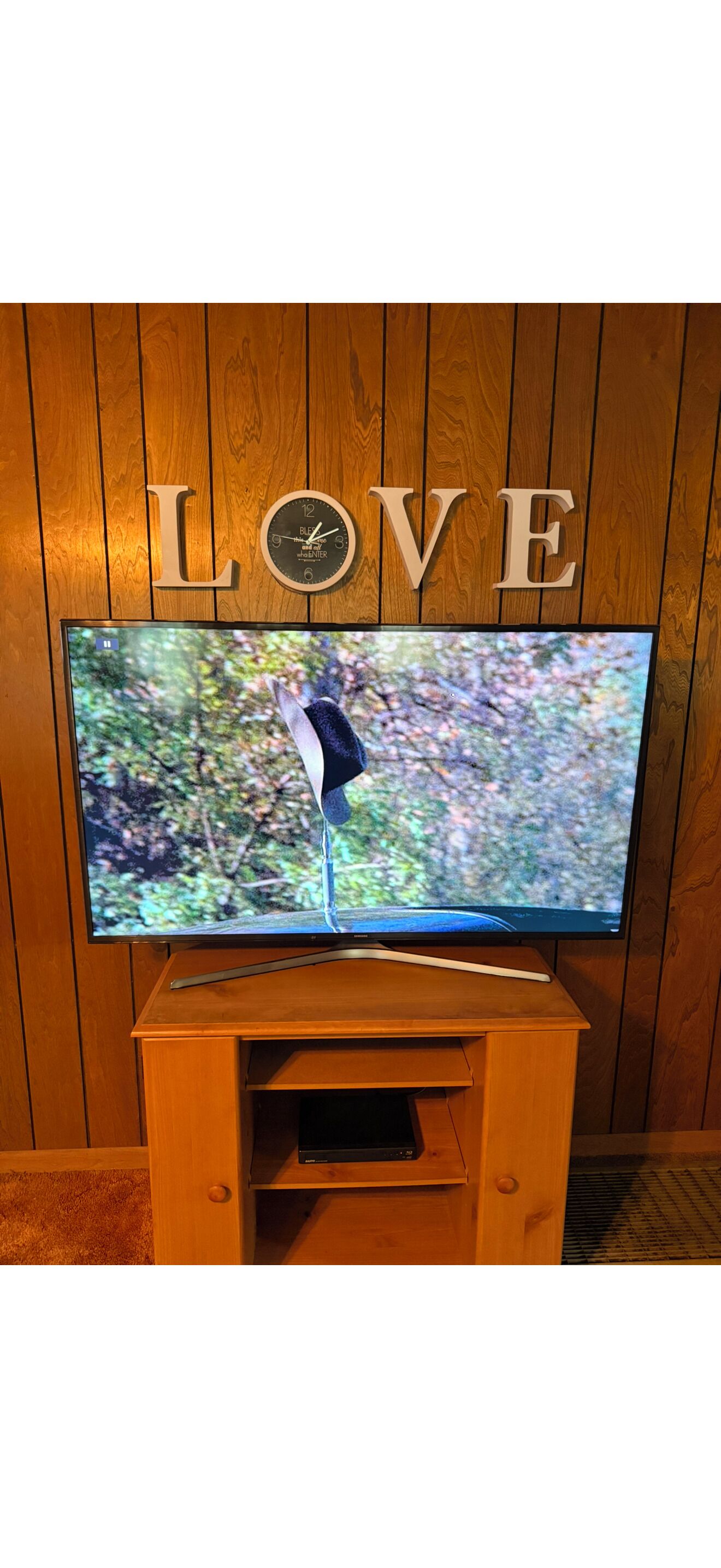 A television on a wooden stand with a 'LOVE' sign above it.