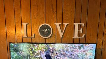 A television on a wooden stand with a 'LOVE' sign above it.