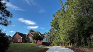 A residential street with two houses, a clear sky, and a sidewalk.