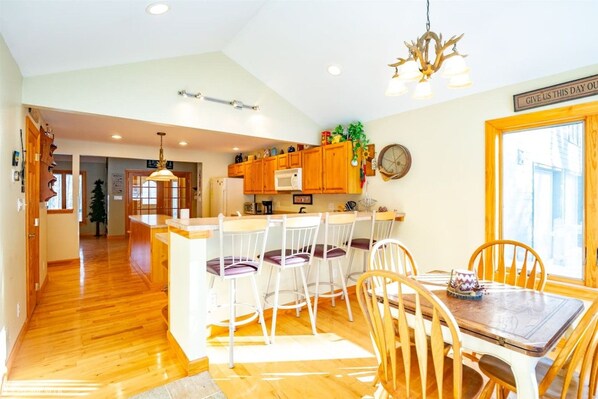 A kitchen with wooden cabinets, a microwave, and a dining area with chairs and a table.