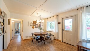 Zona pranzo con tavolo e sedie in legno, un lampadario e una finestra con tende.