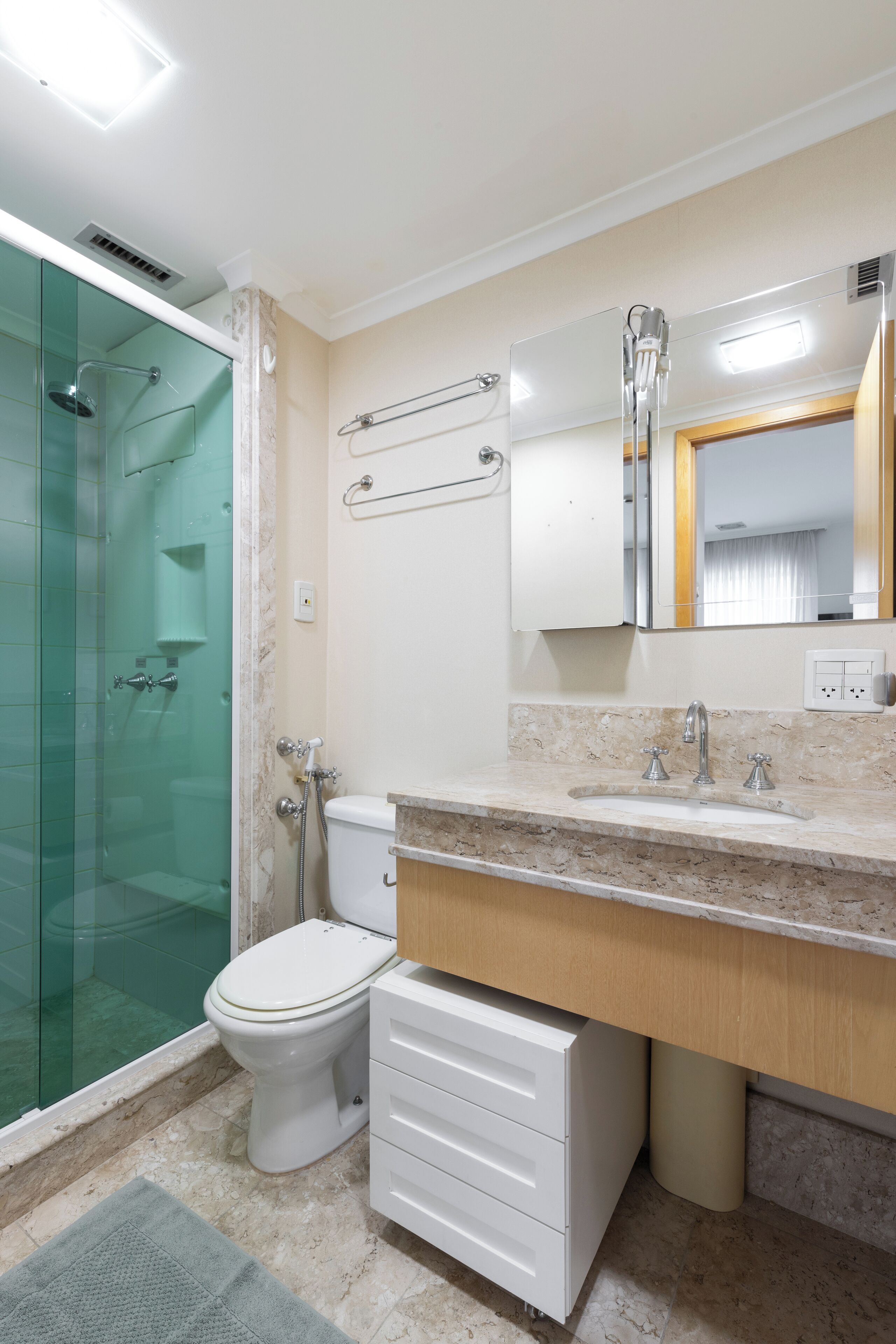 Une salle de bain moderne avec une douche à parois de verre, des toilettes, un lavabo doté d’un plan de travail en marbre et un miroir au-dessus du lavabo.