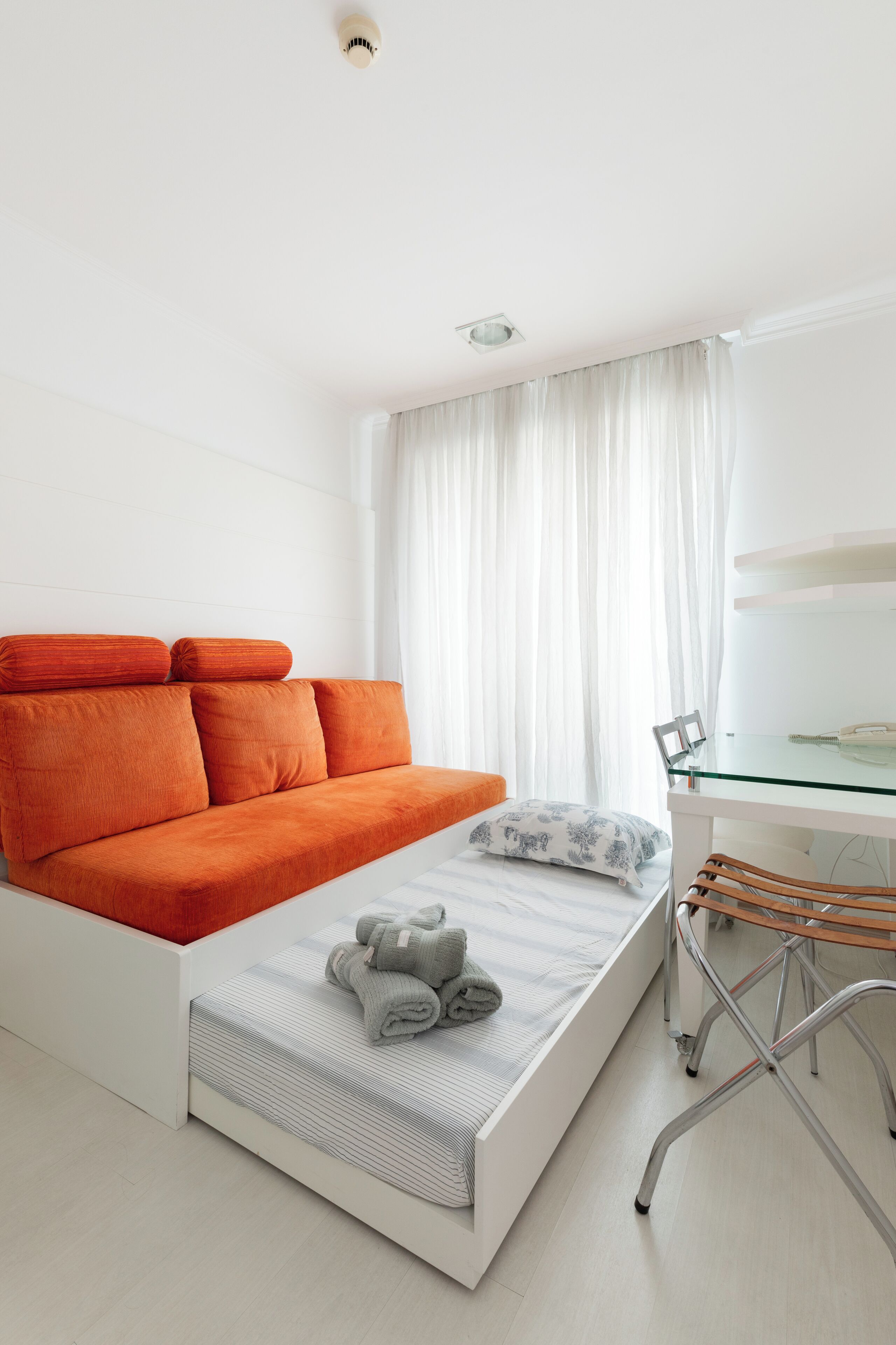 A modern bedroom with a sofa bed, a small table, and a chair.