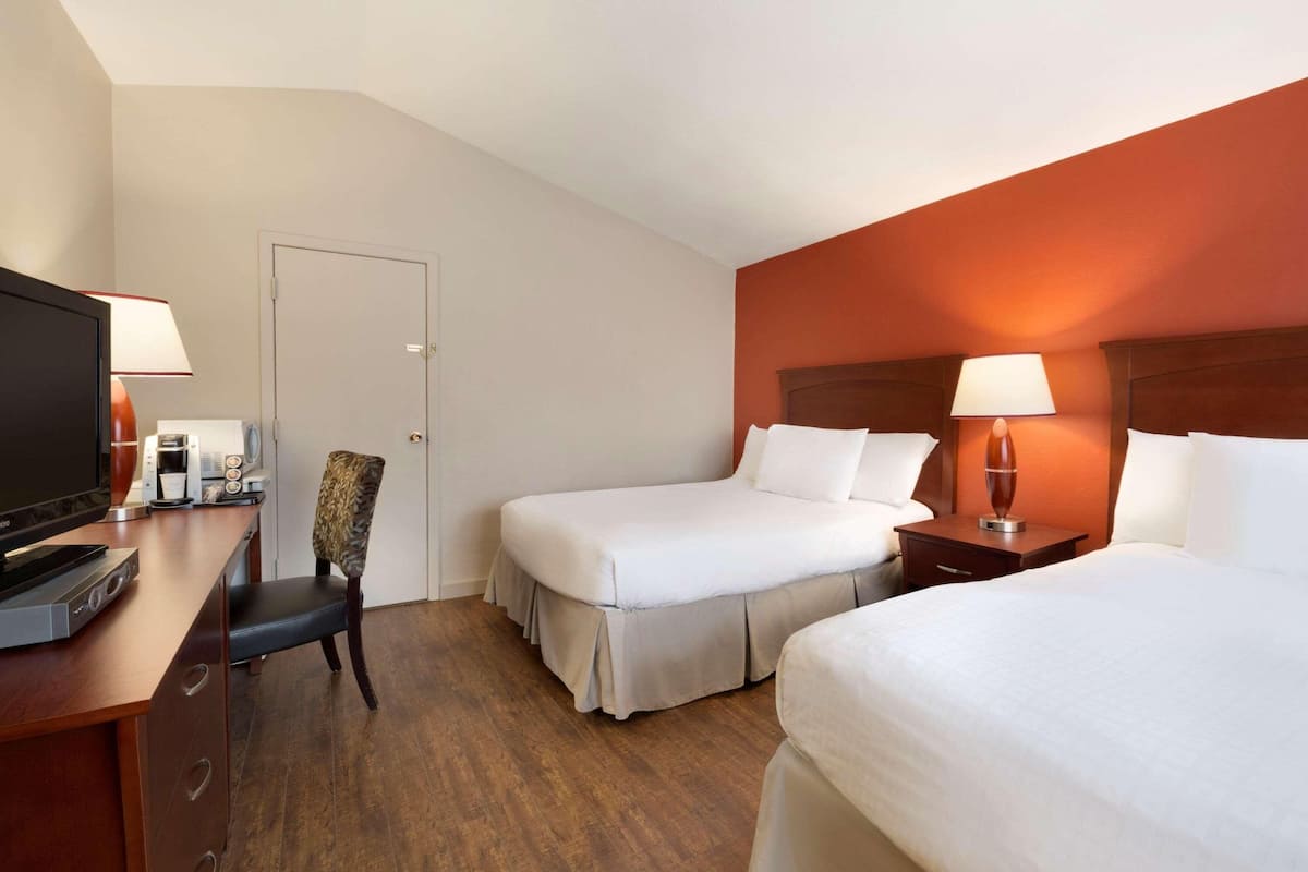 Een hotelkamer met twee bedden, een bureau met een televisie en een stoel.
