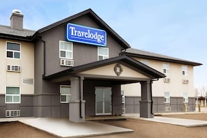 Un hotel Travelodge con un letrero llamativo, una entrada cubierta y un techo plano.