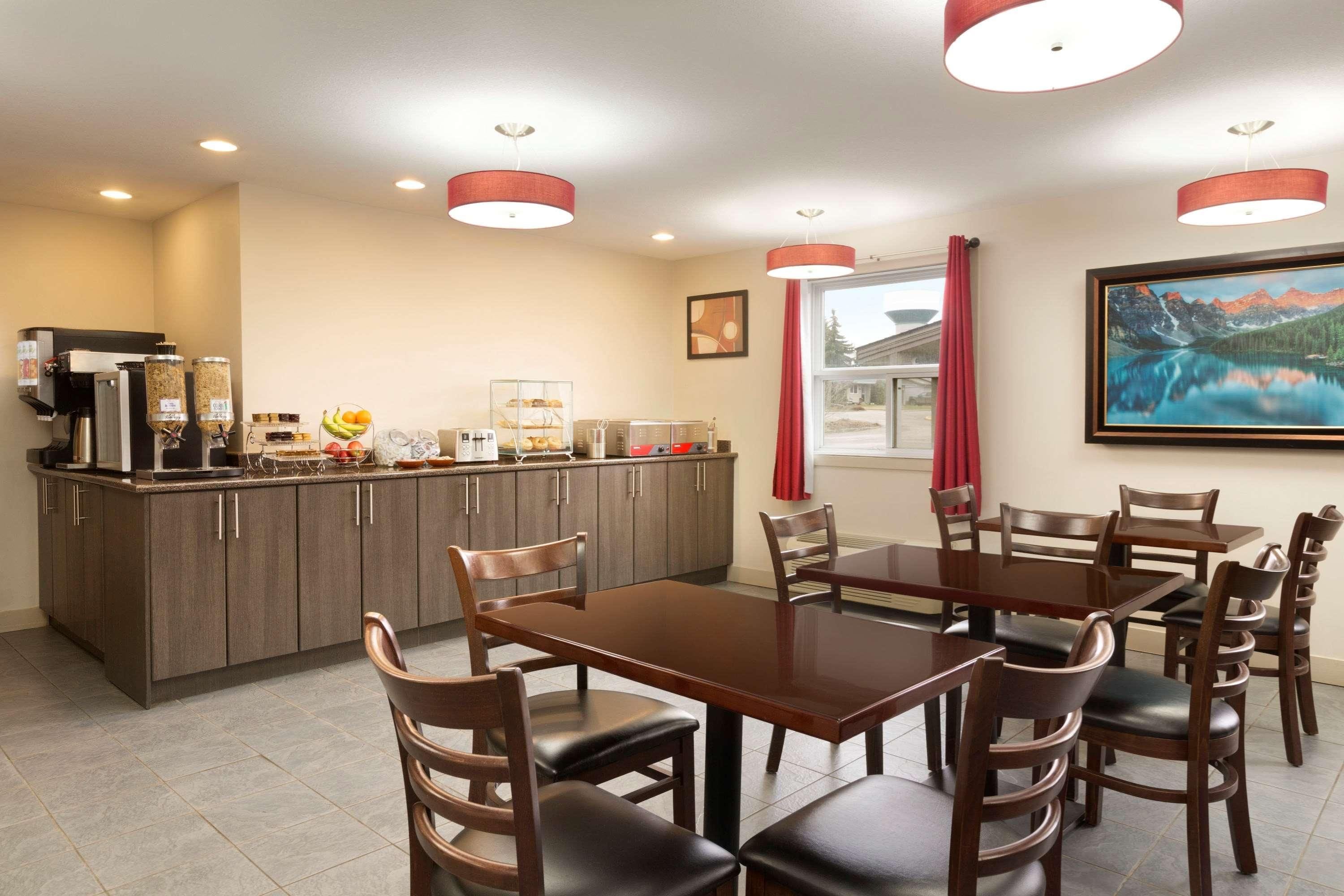 A dining area with a wooden table and chairs, a kitchen with a coffee machine, and a painting on the wall.