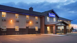 Een Travelodge hotel met een modern design, met een goed verlichte ingang en een parkeerplaats.