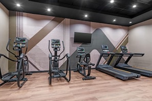 A gym with treadmills, elliptical machines, and a stationary bike, featuring geometric wall patterns and a flat-screen TV. - Drury Inn Pikes Peak Colorado Springs (Colorado Springs)